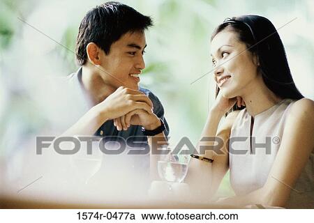 Young couple sitting together at a table View Large Photo Image Stock Image - Young couple sitting together at a table. Fotosearch