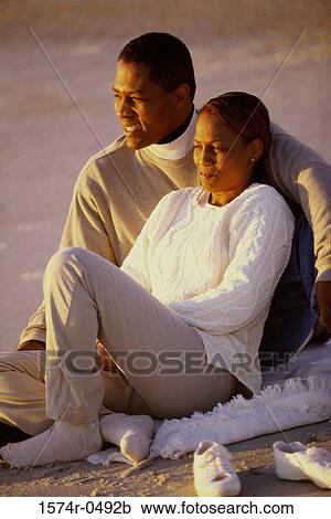 Young couple sitting together at the beach View Large Photo Image Stock Image - Young couple sitting together at the beach. Fotosearch
