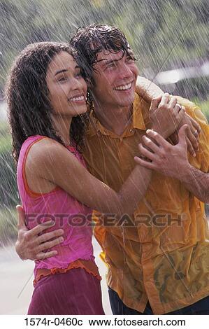 Stock Image - Young couple standing in the rain. Fotosearch