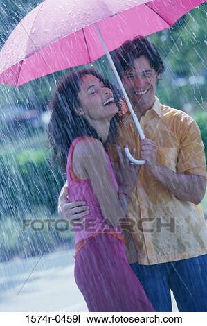 Young couple standing under an umbrella View Large Photo Image Stock Image - Young couple standing under an umbrella. Fotosearch