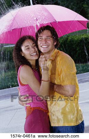 Young couple standing under an umbrella View Large Photo Image Stock Image - Young couple standing under an umbrella. Fotosearch