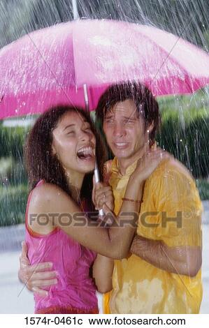 Young couple standing under an umbrella View Large Photo Image Stock Image - Young couple standing under an umbrella. Fotosearch