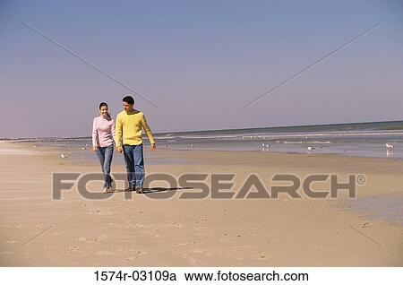 Stock Image - Young couple walking on the beach. Fotosearch