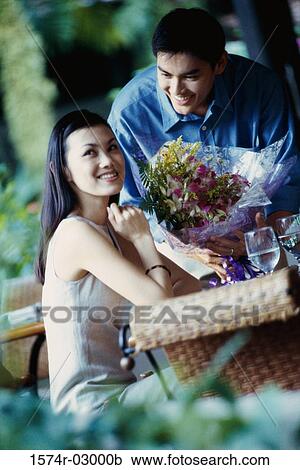 Young man giving a bouquet of flowers to a young woman View Large Photo Image Stock Image - Young man giving a bouquet of flowers to a young woman. Fotosearch