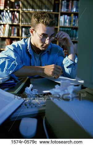 Young man sitting in front of a computer monitor View Large Photo Image Stock Image - Young man sitting in front of a computer monitor. Fotosearch