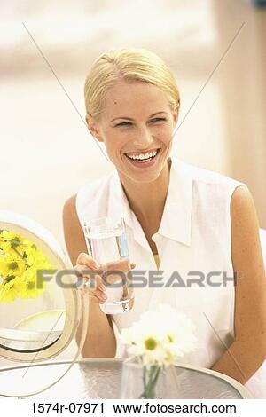 Young woman holding a glass of water View Large Photo Image Stock Image - Young woman holding a glass of water. Fotosearch