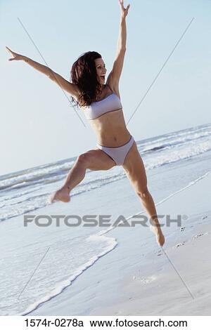 Young woman jumping at the beach View Large Photo Image Stock Image - Young woman jumping at the beach. Fotosearch