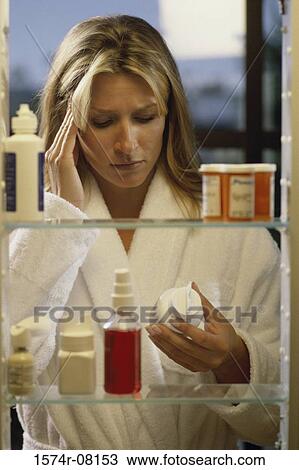 Young woman looking at a bottle of pills View Large Photo Image Stock Image - Young woman looking at a bottle of pills. Fotosearch