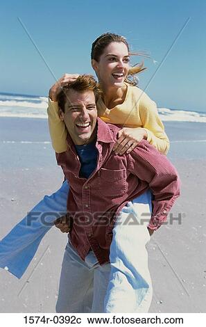 Young woman riding piggyback on a young man at the beach View Large Photo Image Stock Image - Young woman riding piggyback on a young man at the beach. Fotosearch