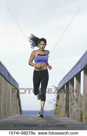 Stock Image - Young woman running with headphones. Fotosearch