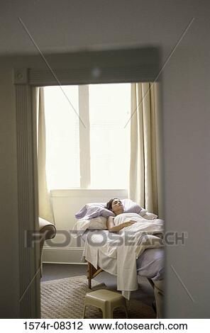 Young woman sleeping on a bed seen through a doorway View Large Photo Image Stock Image - Young woman sleeping on a bed seen through a doorway. Fotosearch