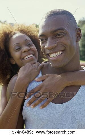 Young woman standing behind a young man with her arms around him View Large Photo Image Stock Image - Young woman standing behind a young man with her arms around him. Fotosearch