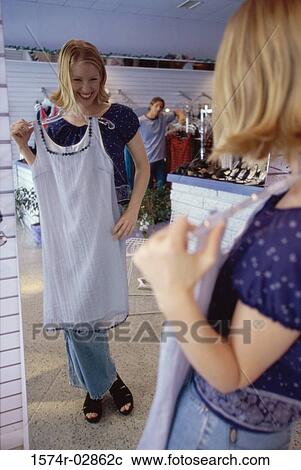 Young woman trying on clothes in a clothing store View Large Photo Image Stock Image - Young woman trying on clothes in a clothing store. Fotosearch