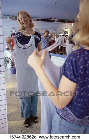 Young woman trying on clothes in a clothing store View Large Photo Image Stock Image - Young woman trying on clothes in a clothing store. Fotosearch