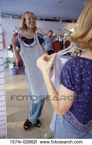 Stock Image - Young woman trying on clothes in a clothing store. Fotosearch