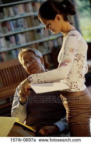 Stock Image - Young woman with a mid adult man in a library. Fotosearch