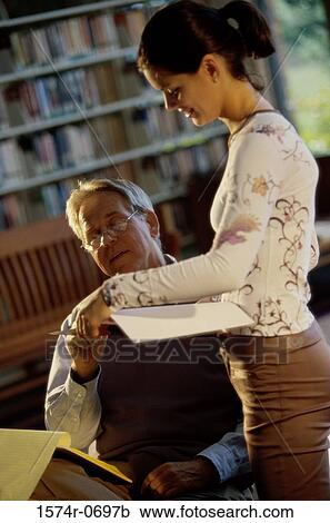 Stock Image - Young woman with a mid adult man in a library. Fotosearch