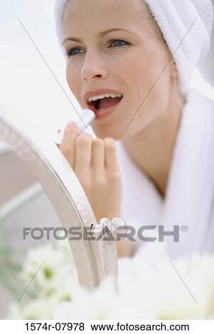 Young woman wrapped in a towel applying lipstick View Large Photo Image Stock Photo - Young woman wrapped in a towel applying lipstick. Fotosearch