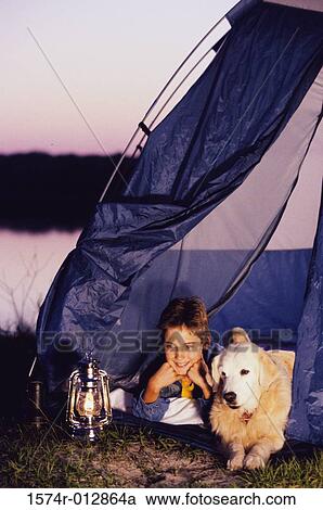 Stock Image - Boy camping in a tent with his dog. Fotosearch
