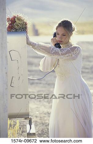 Stock Image - Bride talking on a payphone. Fotosearch