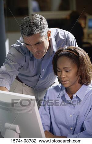 Businessman and a businesswoman working in front of a computer monitor View Large Photo Image Stock Image - Businessman and a businesswoman working in front of a computer monitor. Fotosearch