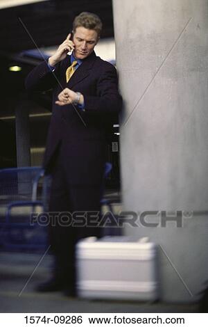 Businessman leaning against a pillar talking on a mobile phone View Large Photo Image Stock Photograph - Businessman leaning against a pillar talking on a mobile phone. Fotosearch