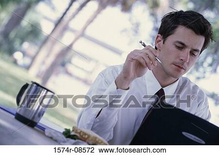 Businessman sitting in front of a laptop View Large Photo Image Stock Image - Businessman sitting in front of a laptop. Fotosearch