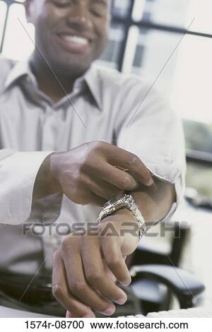 Businessman smiling while rolling up his sleeves View Large Photo Image Stock Image - Businessman smiling while rolling up his sleeves. Fotosearch