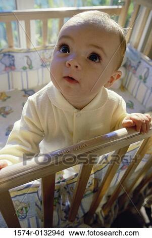 Stock Image - Close-up of a baby boy standing in a crib. Fotosearch
