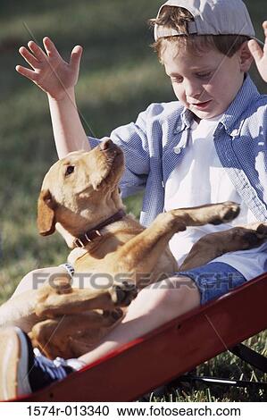 Stock Image - Close-up of a boy sitting in a wagon with his dog. Fotosearch