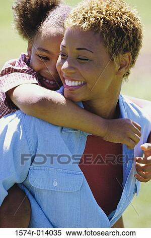 Close-up of a daughter riding piggyback on her mother View Large Photo Image Stock Photography - Close-up of a daughter riding piggyback on her mother. Fotosearch