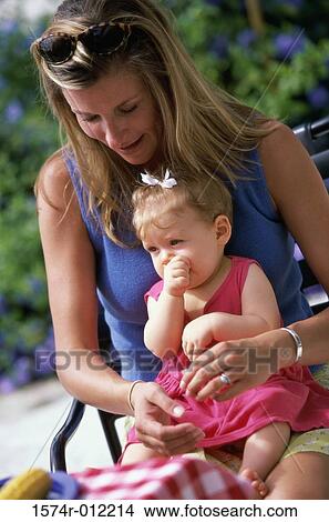 Close-up of a daughter sitting on her mother's lap sucking her thumb View Large Photo Image Picture - Close-up of a daughter sitting on her mother's lap sucking her thumb. Fotosearch