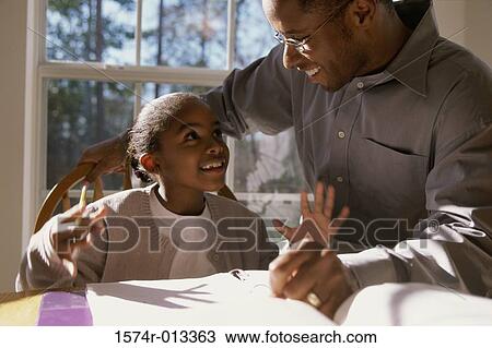 Close-up of a father helping his daughter with her homework View Large Photo Image Stock Image - Close-up of a father helping his daughter with her homework. Fotosearch