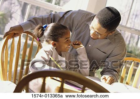 Stock Image - Close-up of a father helping his daughter with her homework. Fotosearch