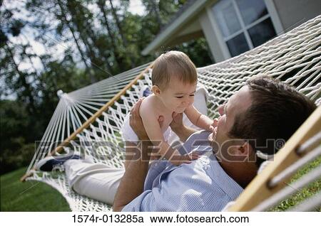 Stock Image - Close-up of a father playing with his son in a hammock. Fotosearch