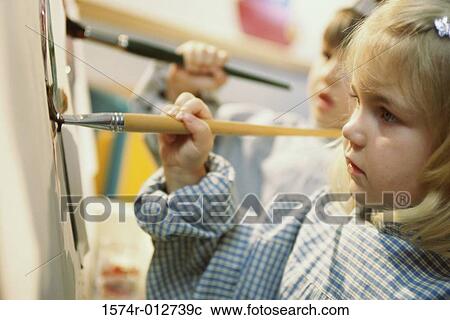 Stock Image - Close-up of a girl and boy painting with paintbrushes. Fotosearch