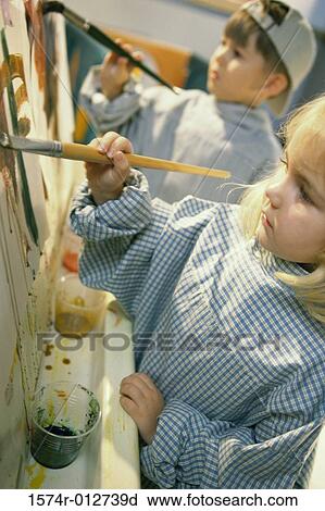 Stock Image - Close-up of a girl and boy painting with paintbrushes. Fotosearch