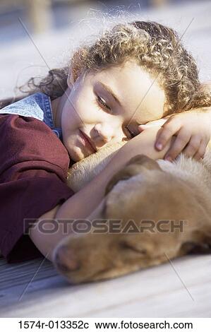 Stock Image - Close-up of a girl sleeping with her dog. Fotosearch