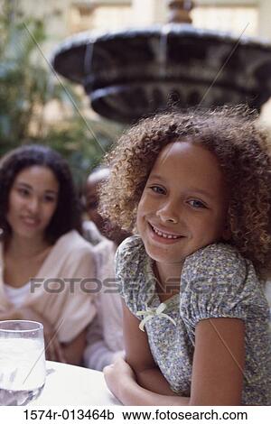 Close-up of a girl smiling with her mother sitting behind View Large Photo Image Stock Image - Close-up of a girl smiling with her mother sitting behind. Fotosearch