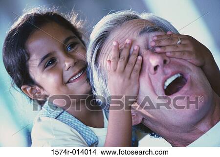 Picture - Close-up of a granddaughter covering her grandfather's eyes. Fotosearch