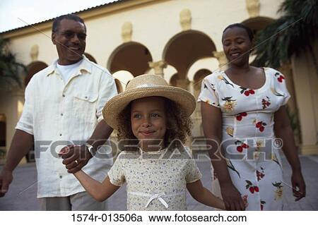 Stock Image - Close-up of a granddaughter holding hands with her grandparents and walking. Fotosearch