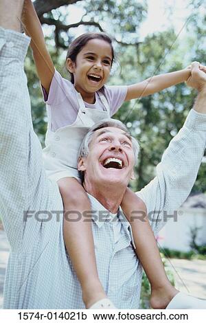 Stock Image - Close-up of a grandfather carrying his granddaughter on his shoulders. Fotosearch