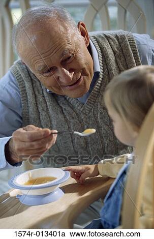 Stock Image - Close-up of a grandfather feeding his grandson. Fotosearch