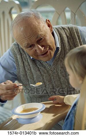 Close-up of a grandfather feeding his grandson View Large Photo Image Stock Image - Close-up of a grandfather feeding his grandson. Fotosearch