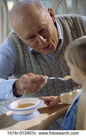 Close-up of a grandfather feeding his grandson View Large Photo Image Stock Image - Close-up of a grandfather feeding his grandson. Fotosearch
