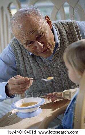 Stock Image - Close-up of a grandfather feeding his grandson. Fotosearch