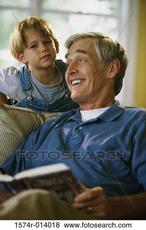 Stock Photo - Close-up of a grandfather holding a book with his grandson behind him. Fotosearch