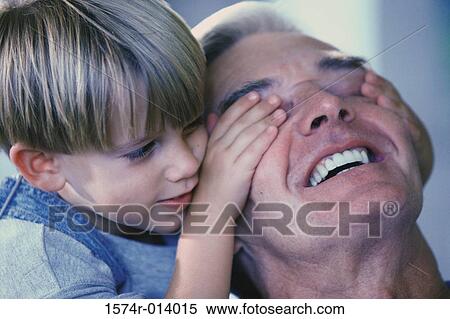 Stock Photography - Close-up of a grandson covering his grandfather's eyes. Fotosearch