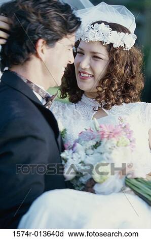 Stock Image - Close-up of a groom carrying his bride. Fotosearch