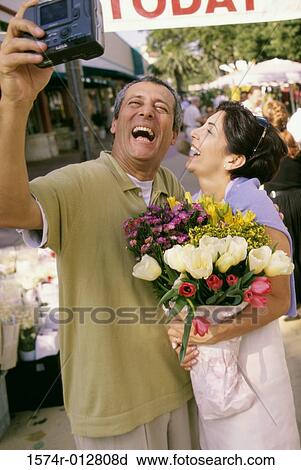 Close-up of a mature couple taking a photograph of themselves in a market View Large Photo Image Stock Image - Close-up of a mature couple taking a photograph of themselves in a market. Fotosearch
